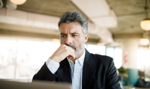 A concerned businessman working at his computer in an office.