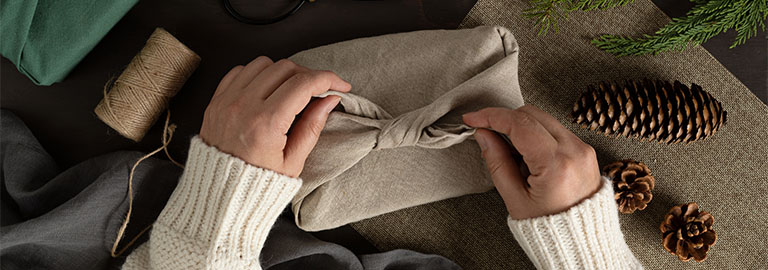 Two hands showing wrapping a present in material.