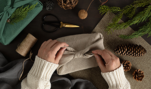 Two hands showing wrapping a present in material.